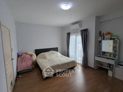 Cozy bedroom with wooden flooring and natural light, featuring a comfortable bed and a stylish vanity.