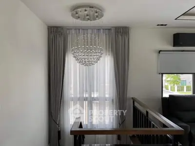 Modern interior with elegant chandelier and floor-to-ceiling window, showcasing contemporary design.