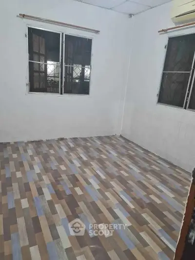 Spacious empty room with modern patterned flooring and large windows.