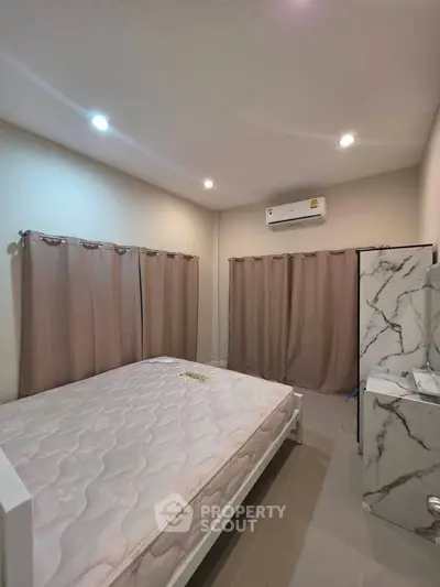Spacious bedroom with modern decor and air conditioning, featuring a comfortable bed and stylish curtains.