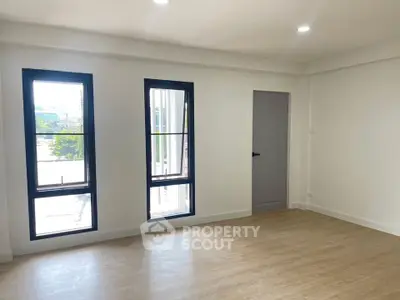 Spacious and bright room with large windows and wooden flooring, perfect for modern living.