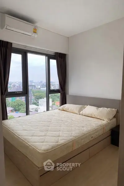Modern bedroom with large windows offering stunning city views and ample natural light.