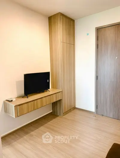 Modern minimalist living room with wooden flooring and compact TV setup.