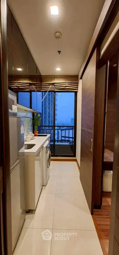 Modern laundry area with washing machine and balcony view in high-rise apartment.