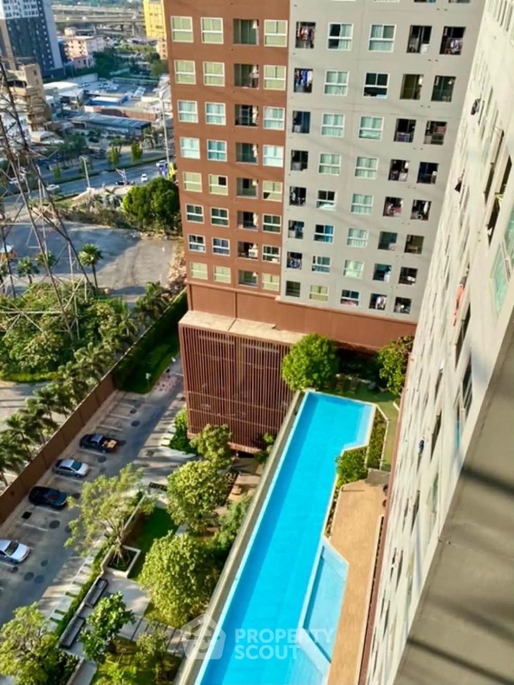 Stunning aerial view of modern high-rise building with luxurious swimming pool and lush greenery.