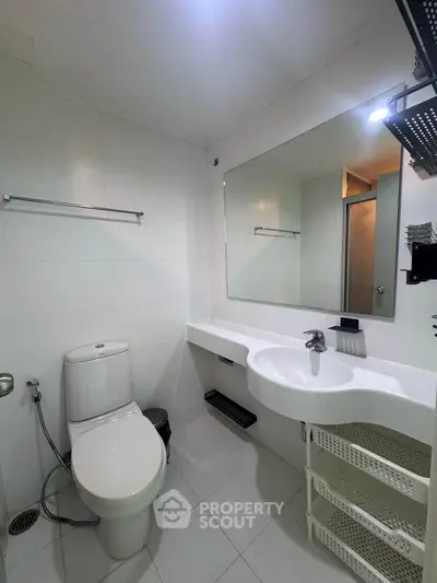 Modern bathroom with sleek white fixtures and spacious mirror in a contemporary apartment.