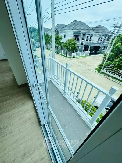 Charming balcony view from modern townhouse with large windows and serene neighborhood.