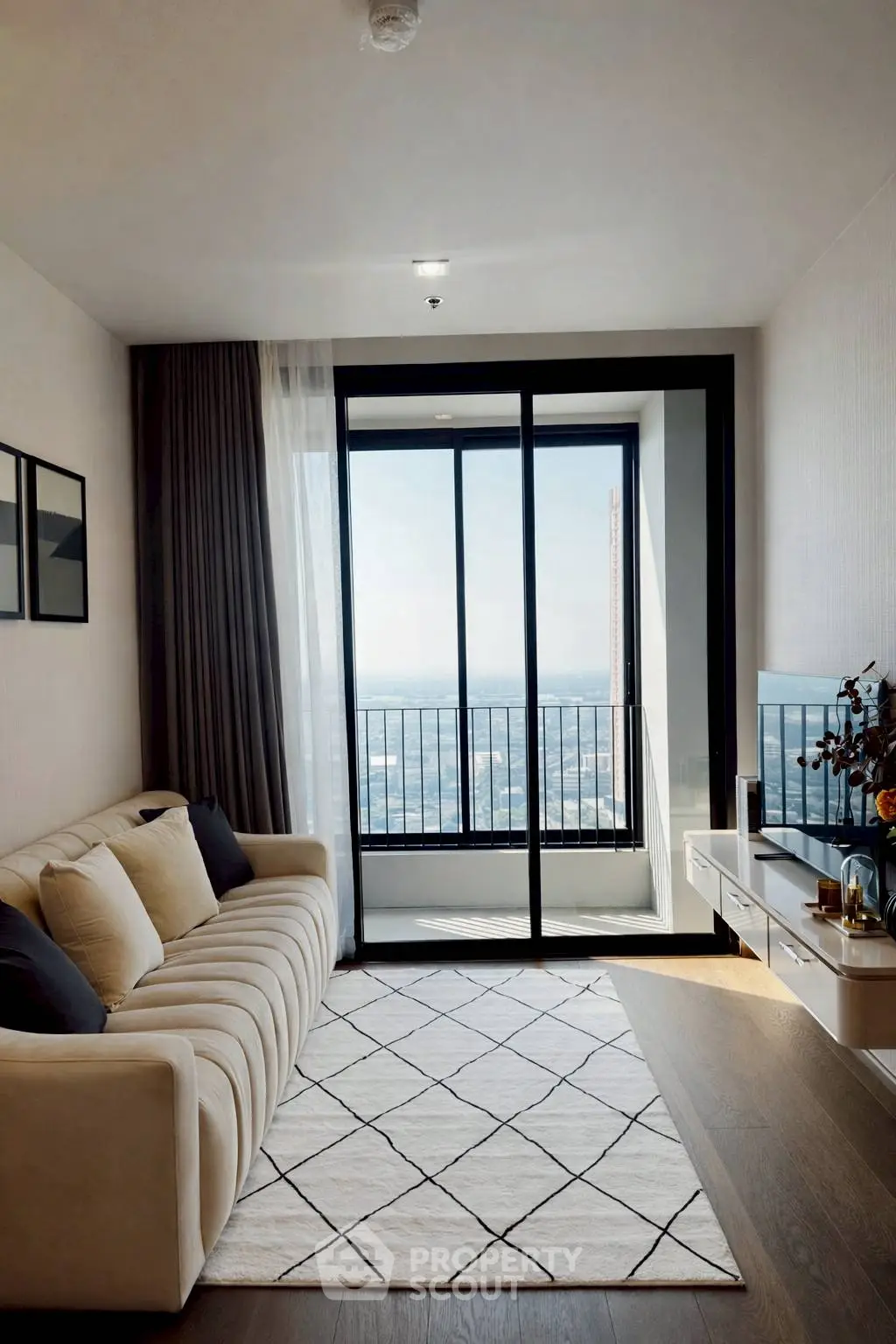 Modern living room with balcony and stunning city view, featuring elegant decor and natural light.