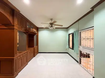 Spacious living room with built-in wooden cabinets and ceiling fan, perfect for cozy family gatherings.