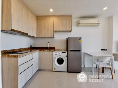 Modern kitchen with sleek cabinets, washing machine, and stainless steel fridge in a bright apartment.