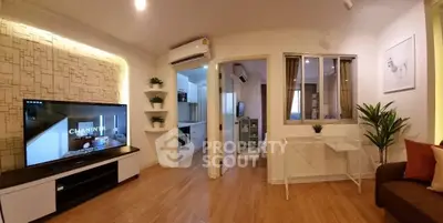 Modern living room with stylish decor and open kitchen layout, featuring a large TV and air conditioning.