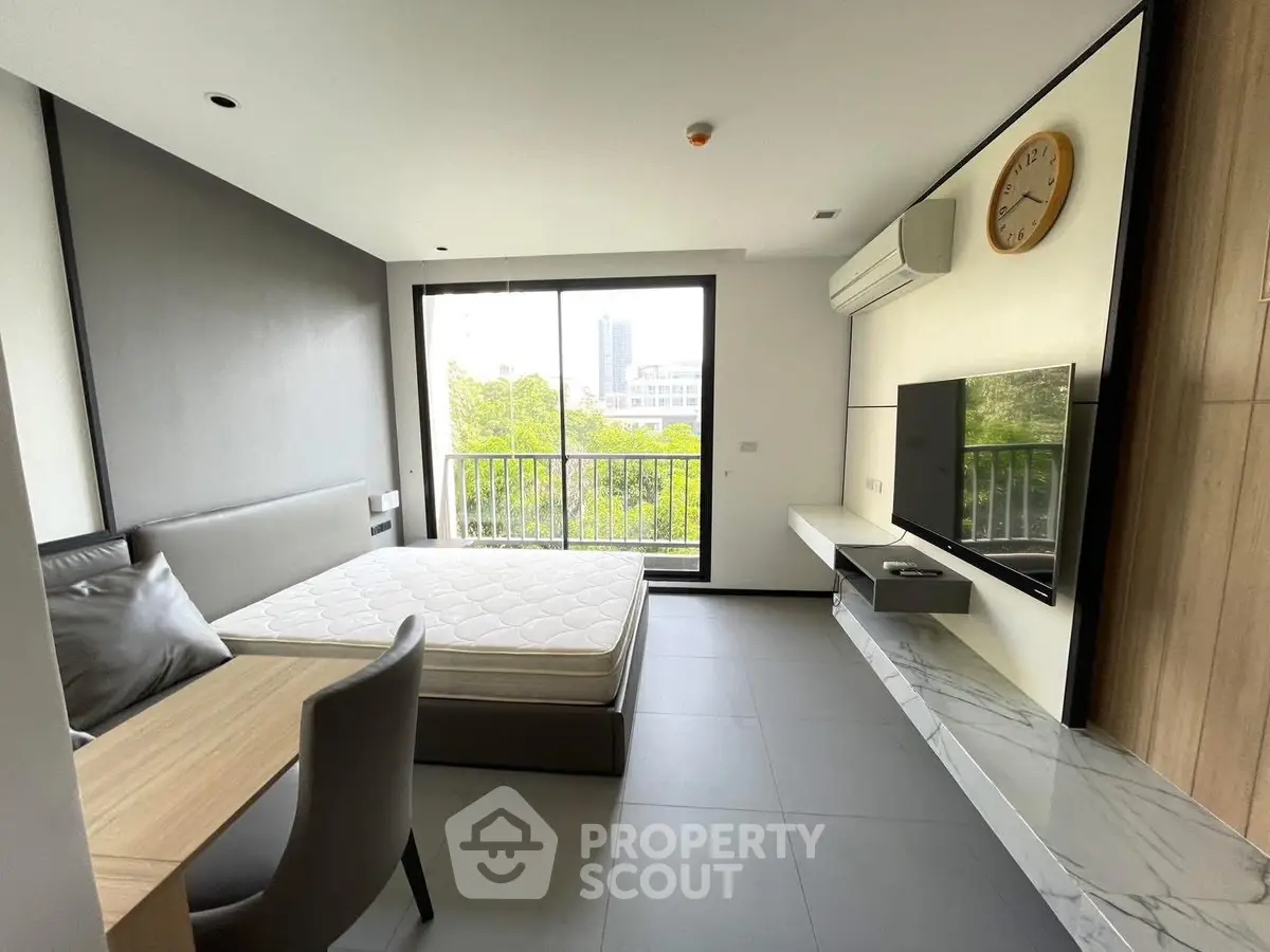 Modern bedroom with large window and city view, featuring sleek furniture and minimalist design.