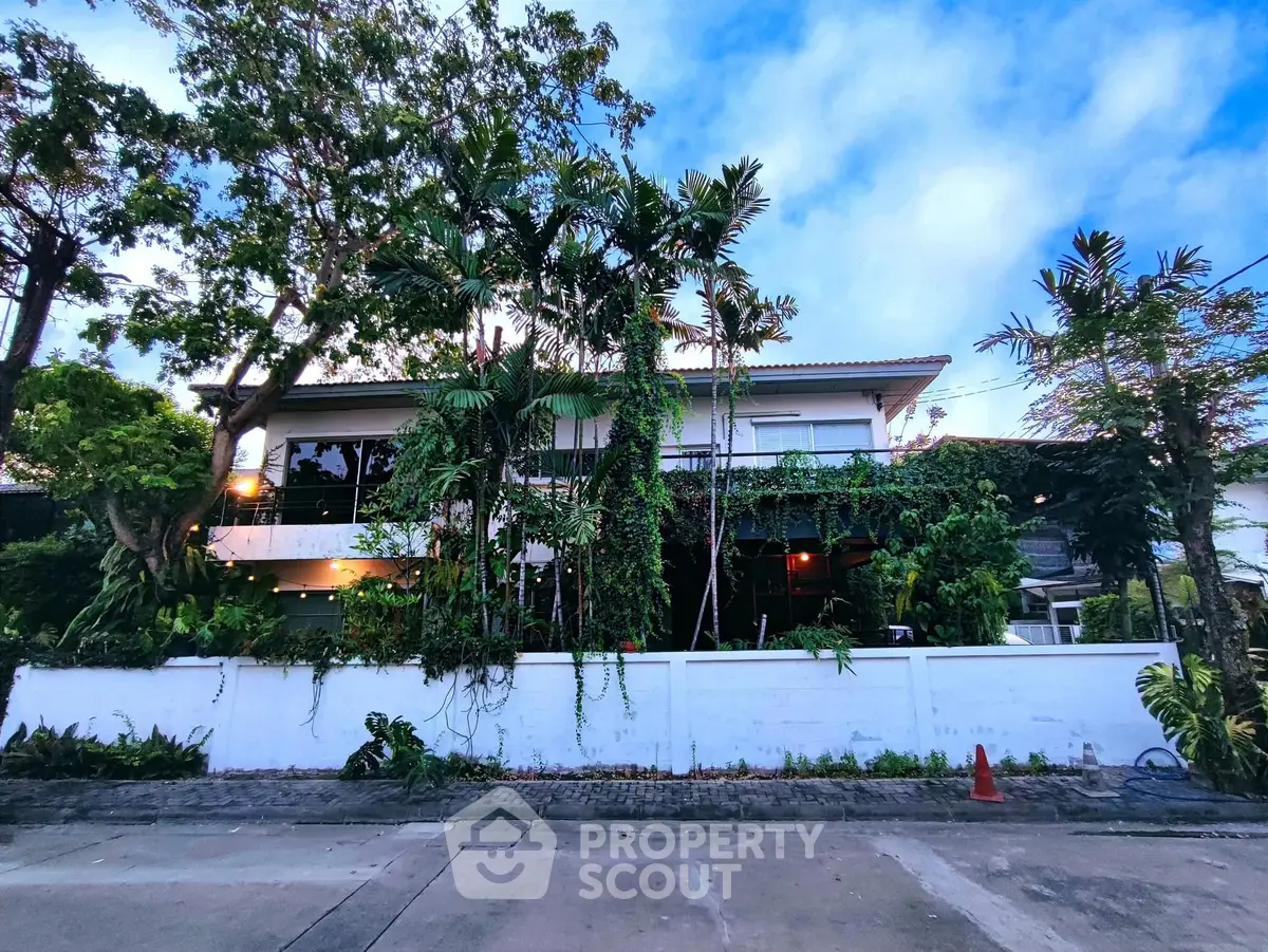 Charming two-story house with lush greenery and modern design in a serene neighborhood.