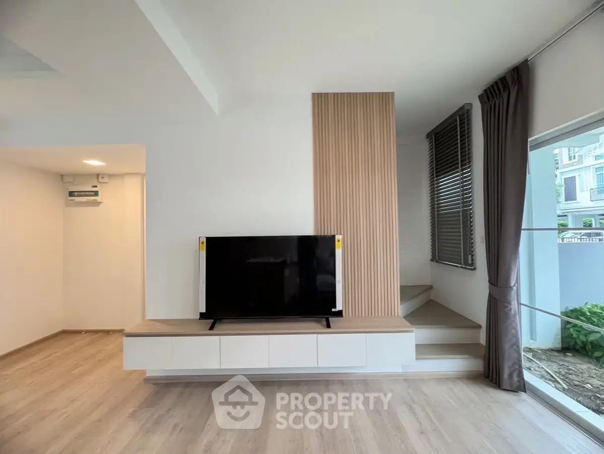 Modern living room with sleek TV setup and stylish wooden paneling.