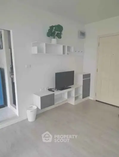 Modern living room with sleek white shelving and TV unit, minimalist decor, and light wood flooring.