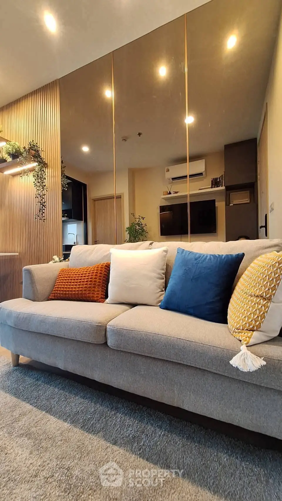Modern living room with stylish sofa and decorative pillows, warm lighting, and elegant wall paneling.