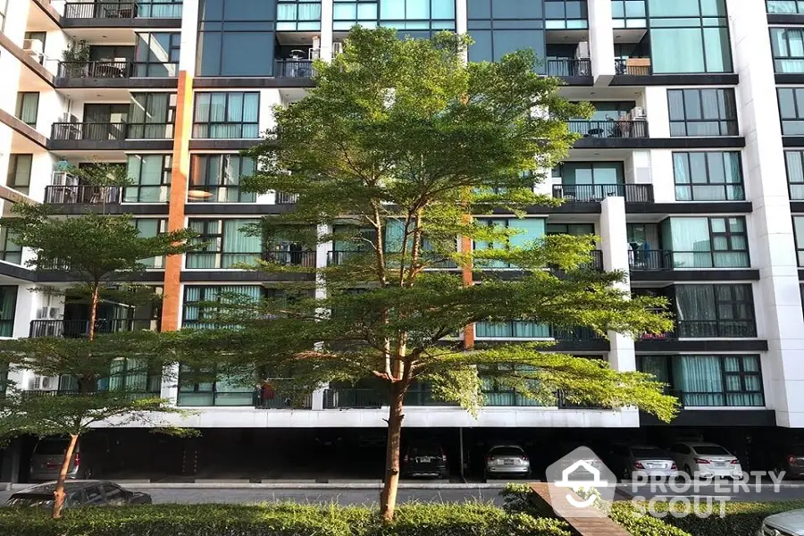 Modern apartment building with lush greenery and parking area