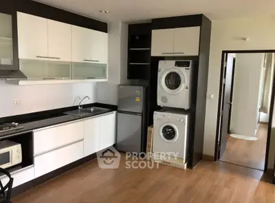Modern kitchen with sleek cabinets, appliances, and in-unit laundry in a stylish apartment.