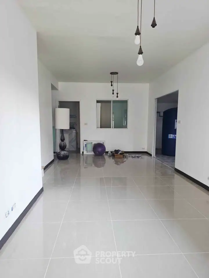 Spacious modern living room with sleek tile flooring and stylish lighting fixtures.