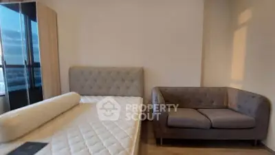 Spacious bedroom with modern furniture and large window view.