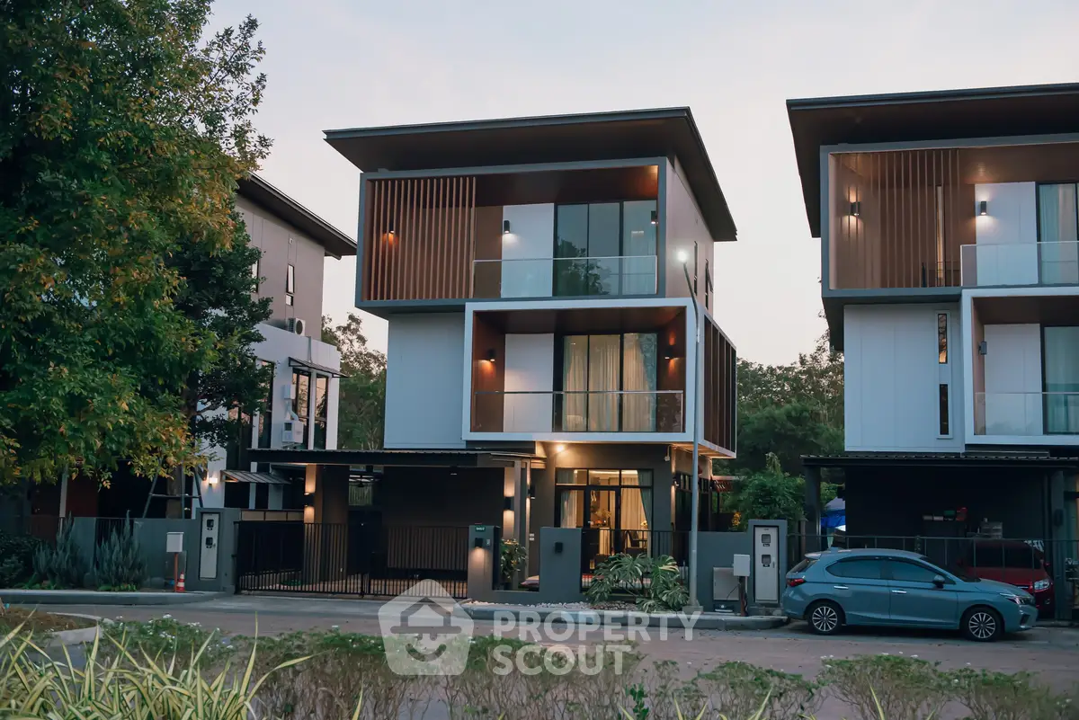 Modern three-story house with sleek design and large windows in a suburban setting.
