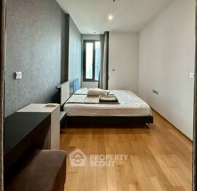 Spacious modern bedroom with wooden flooring and large window