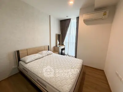 Modern bedroom with wooden flooring and air conditioning in a cozy apartment.