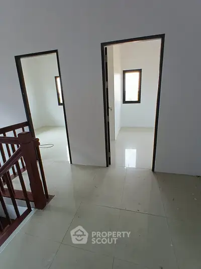 Spacious interior with tiled flooring and natural light, featuring two doorways and a staircase.