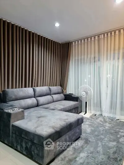Luxurious living room with plush gray sofa and elegant curtains, perfect for relaxation and entertainment.