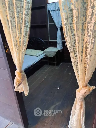 Charming rustic bedroom with wooden floors and lace curtains, perfect for a cozy retreat.