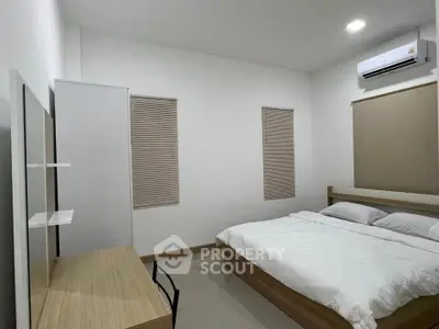 Modern minimalist bedroom with sleek furniture and air conditioning.
