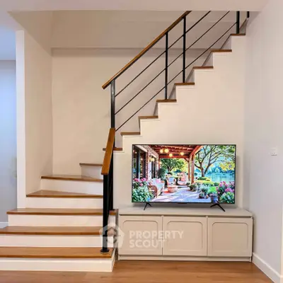 Stylish interior with modern staircase and TV setup in a cozy living space.