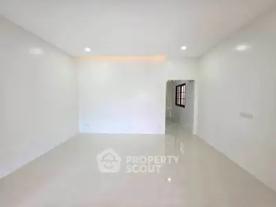 Spacious minimalist living room with white walls and tiled flooring, perfect for modern decor.