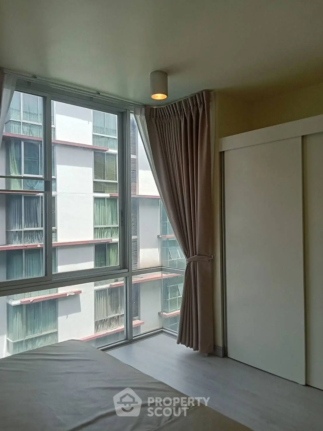 Bright bedroom with large windows and modern curtains in a high-rise building.
