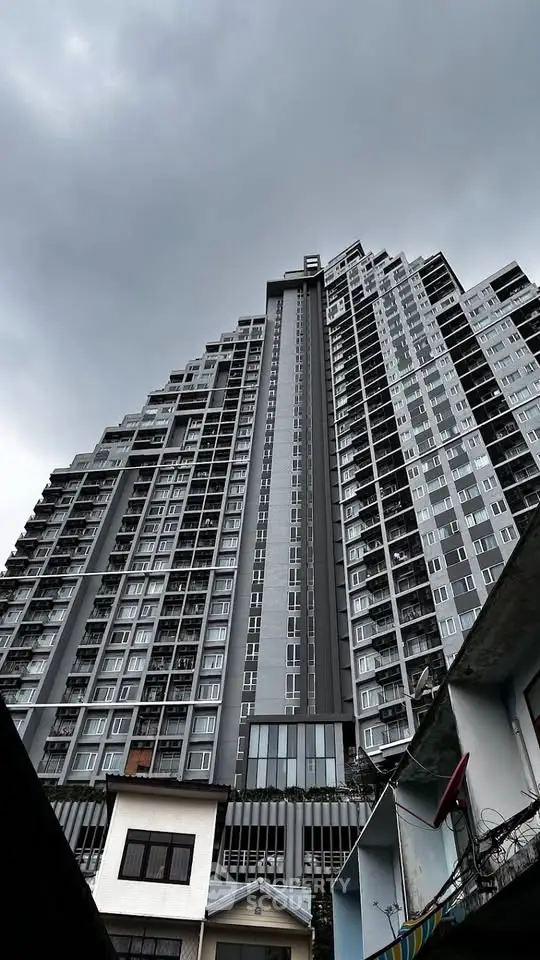 Stunning high-rise building with modern architecture under a dramatic cloudy sky.