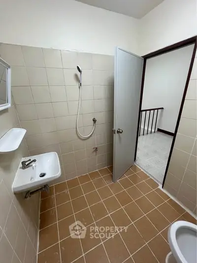 Spacious bathroom with tiled walls and floor, featuring a shower and sink.