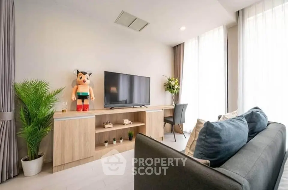 Modern living room with stylish decor and large TV, featuring a cozy sofa and natural light.