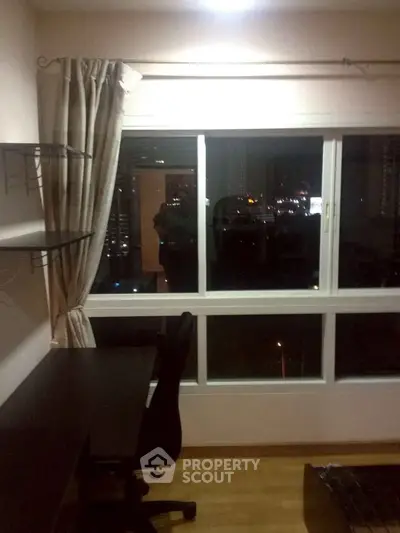 Cozy study room with night city view, featuring a desk and shelves, perfect for work or study.