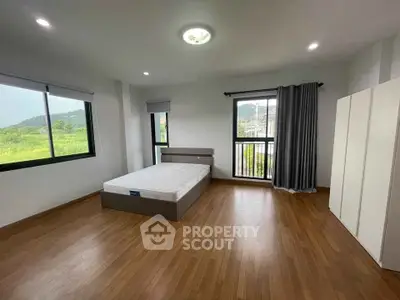 Spacious bedroom with large windows and scenic views, perfect for relaxation and comfort.