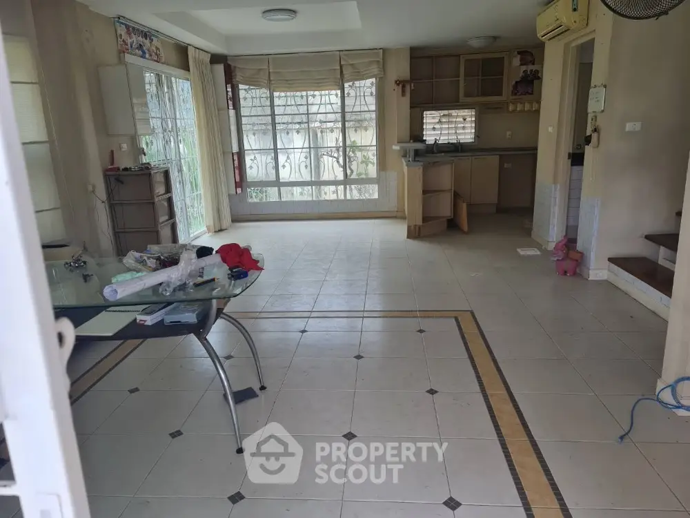 Spacious living room with tiled flooring and large windows in a modern home.