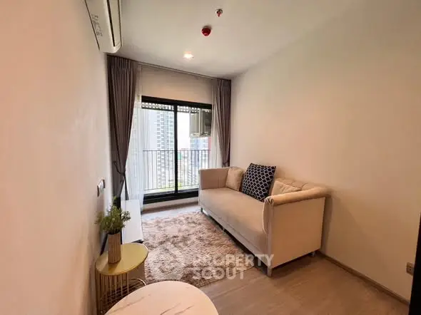 Cozy living room with modern sofa and city view balcony in high-rise apartment.