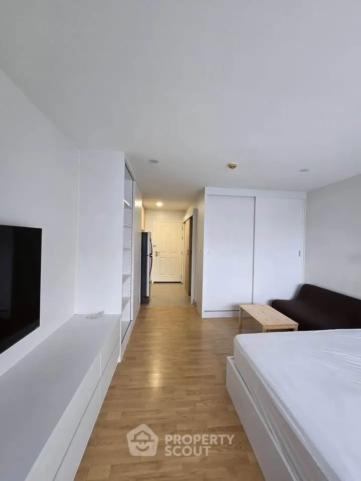 Modern studio apartment with sleek design and wooden flooring, featuring a cozy living area and ample storage space.