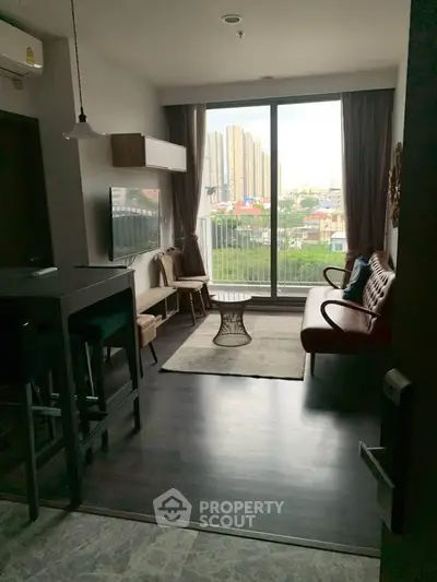 Modern living room with large window and city view, featuring stylish furniture and open layout.