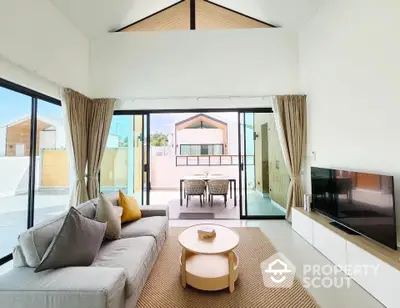 Modern living room with high ceiling and large glass doors leading to balcony