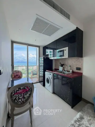 Modern kitchen with sleek black cabinets, washing machine, and stunning city view from large window.