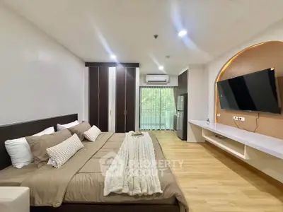 Spacious modern bedroom with large bed, wall-mounted TV, and balcony view.