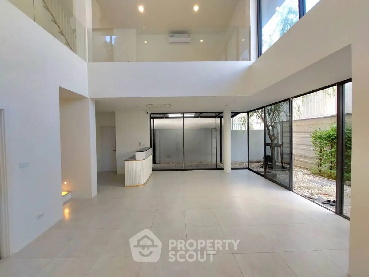 Spacious modern living room with high ceilings and large windows offering natural light.