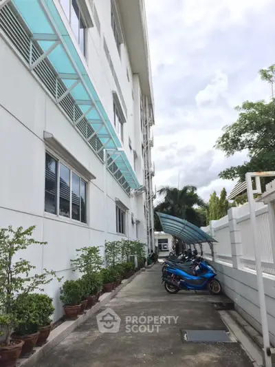 Modern building exterior with motorbike parking and lush greenery