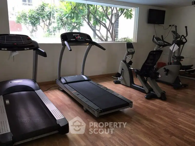 Spacious gym with modern equipment and large window view.