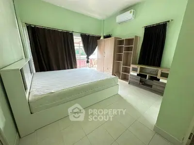 Spacious bedroom with green walls, large windows, and modern furniture in a serene setting.